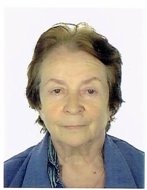 Portrait photo of Monique Arbaud, an older woman with short, light brown hair and light skin, wearing a blue collared shirt, facing the camera against a plain white background.